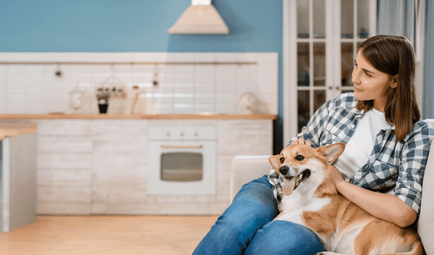 woman sitting on a couch while petting a dog