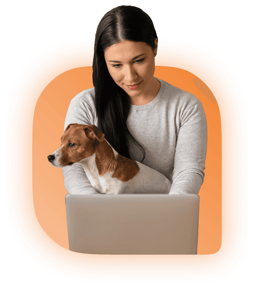 Woman sitting next to a computer with a dog in her lap with an orange background